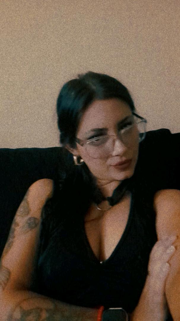 Girl from Argentina in glasses relaxing on a sofa during a cam chat